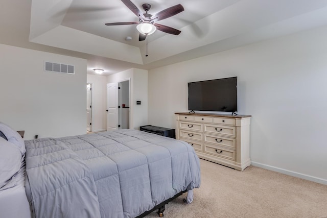 bedroom featuring ceiling fan, a raised ceiling, and light carpet