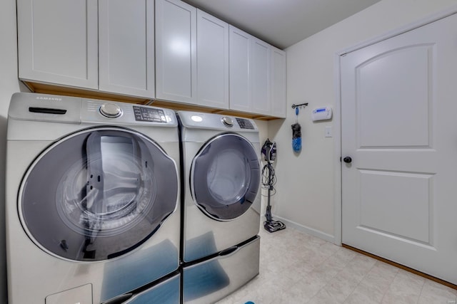 clothes washing area featuring washing machine and dryer and cabinets