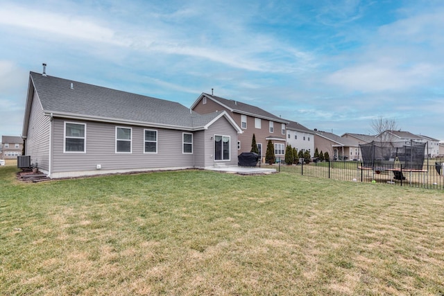 back of property featuring a trampoline, a lawn, central air condition unit, and a patio area