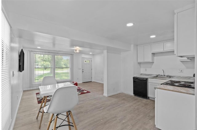 kitchen featuring black dishwasher, light wood finished floors, light countertops, white cabinetry, and a sink