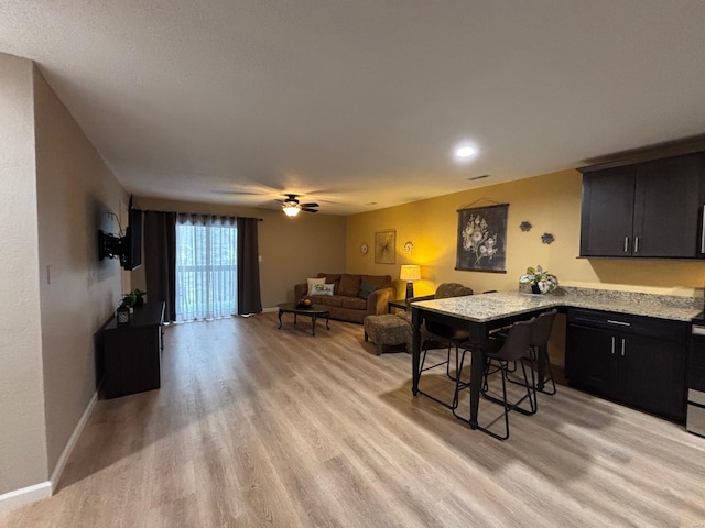 interior space featuring light stone countertops, a breakfast bar, kitchen peninsula, and light wood-type flooring