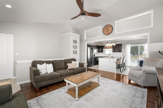 living room featuring recessed lighting, ceiling fan with notable chandelier, wood finished floors, and vaulted ceiling