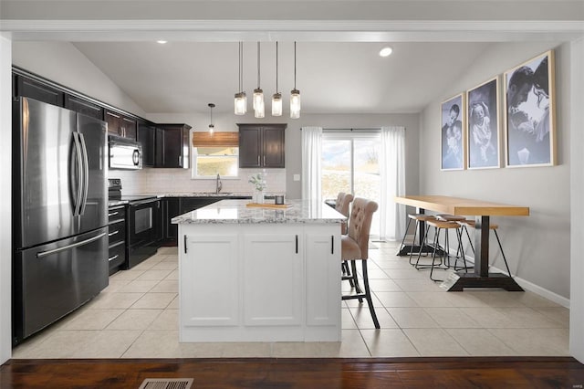 kitchen featuring black electric range, freestanding refrigerator, light tile patterned flooring, and lofted ceiling
