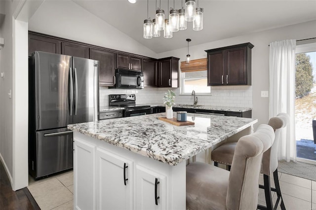 kitchen with lofted ceiling, light tile patterned flooring, dark brown cabinets, and stainless steel appliances