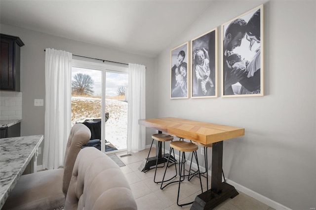 dining space featuring baseboards, light tile patterned floors, and lofted ceiling