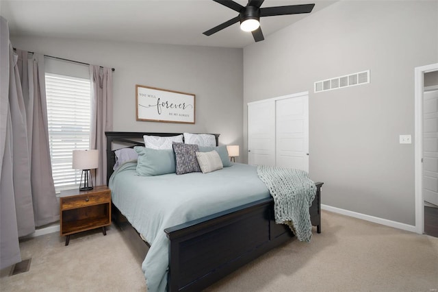 bedroom featuring visible vents, lofted ceiling, a closet, and light colored carpet