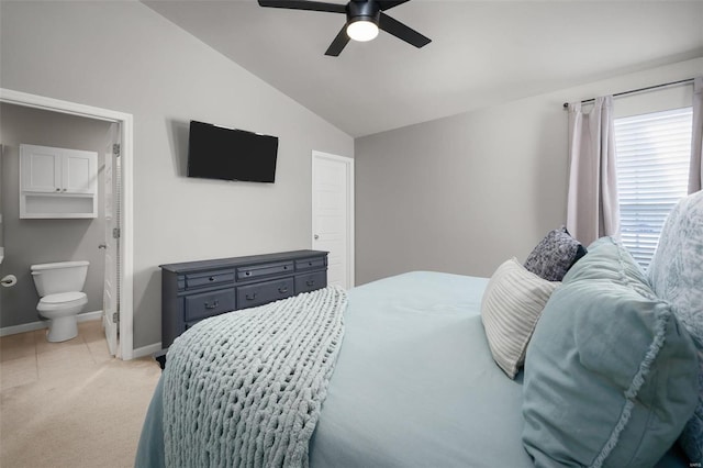 bedroom with connected bathroom, light colored carpet, a ceiling fan, baseboards, and vaulted ceiling