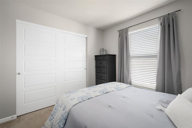 carpeted bedroom featuring baseboards and a closet