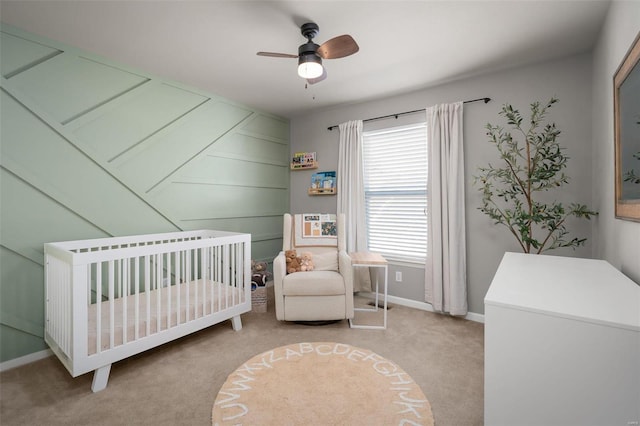 bedroom featuring carpet flooring, baseboards, a crib, and ceiling fan