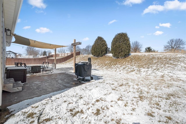 yard covered in snow with fence, a fire pit, and a patio area