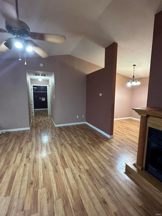 unfurnished living room featuring vaulted ceiling, ceiling fan with notable chandelier, and light wood-type flooring