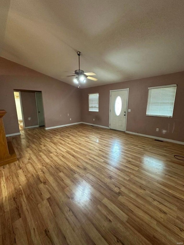 unfurnished living room with lofted ceiling, a textured ceiling, light hardwood / wood-style floors, and ceiling fan