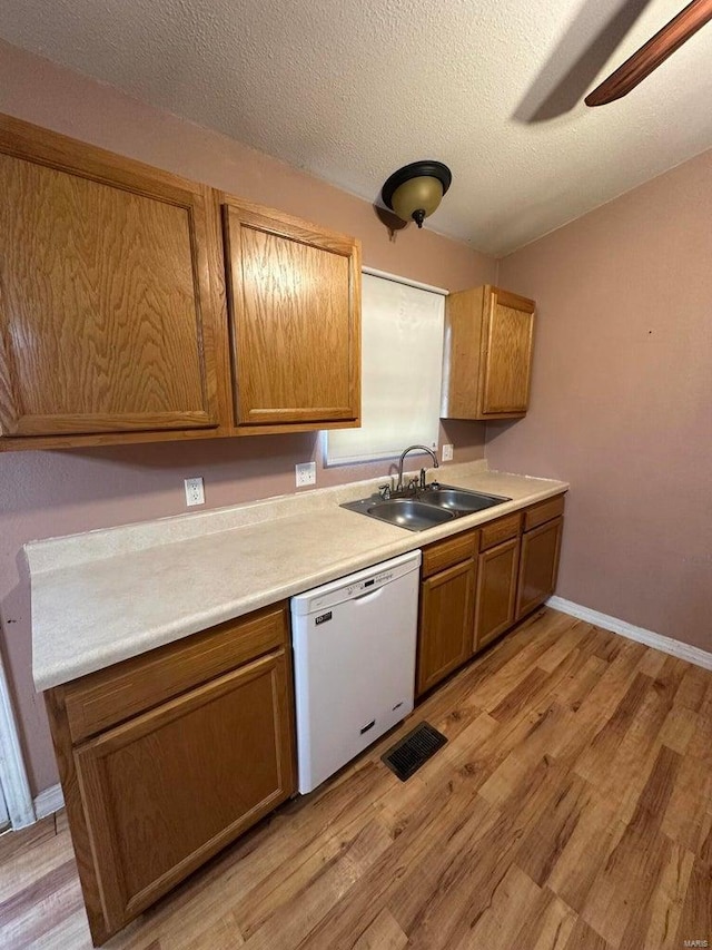 kitchen with dishwasher, sink, ceiling fan, light hardwood / wood-style floors, and a textured ceiling