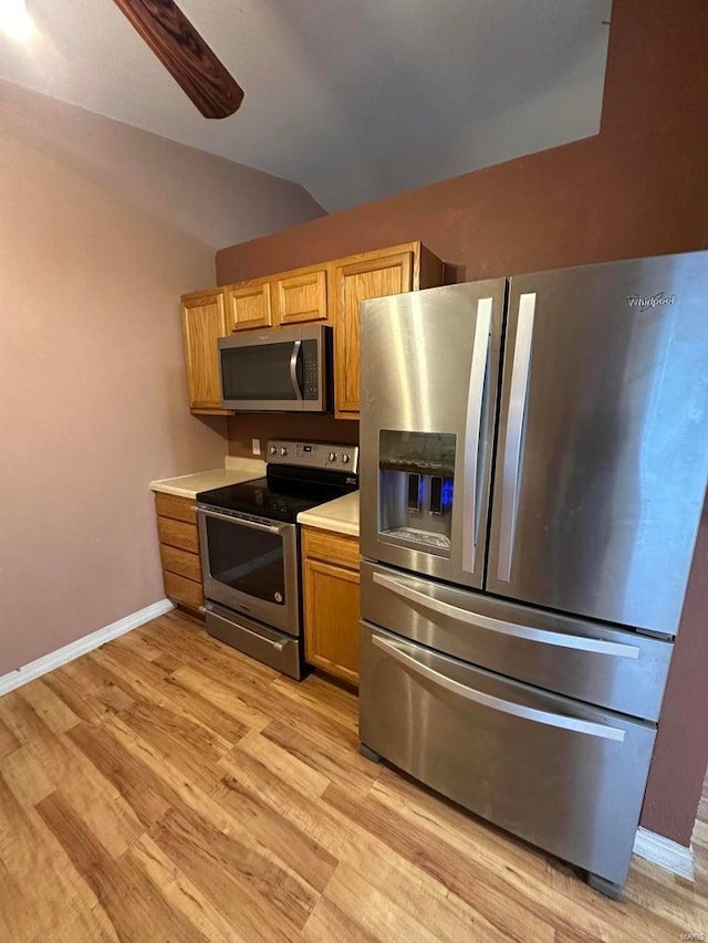 kitchen with vaulted ceiling, stainless steel appliances, ceiling fan, and light wood-type flooring