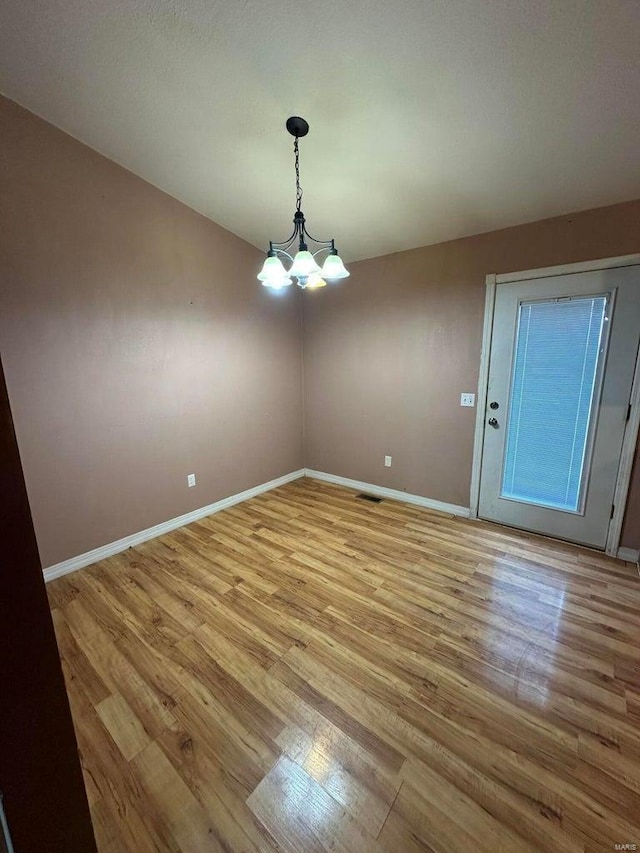 unfurnished dining area with a notable chandelier and light hardwood / wood-style floors