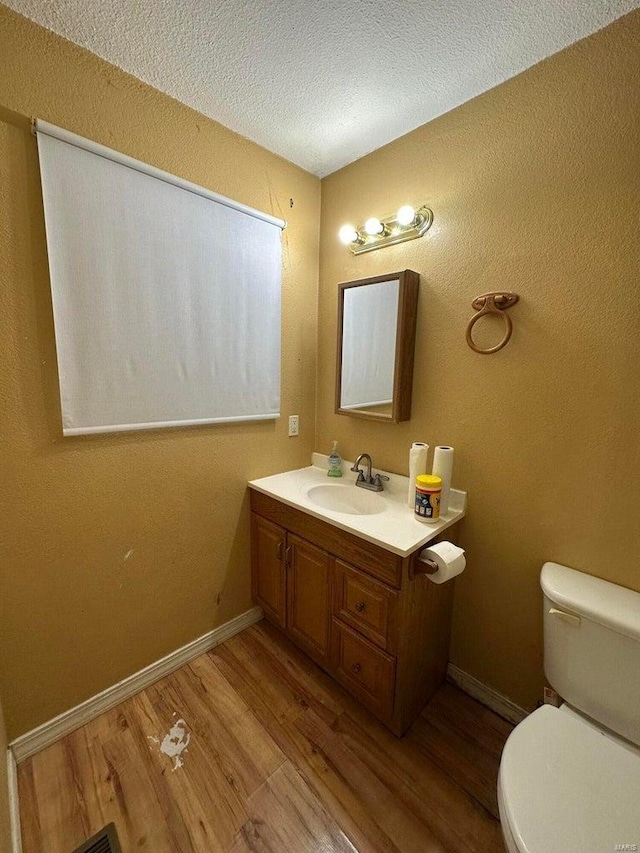 bathroom with vanity, hardwood / wood-style flooring, a textured ceiling, and toilet