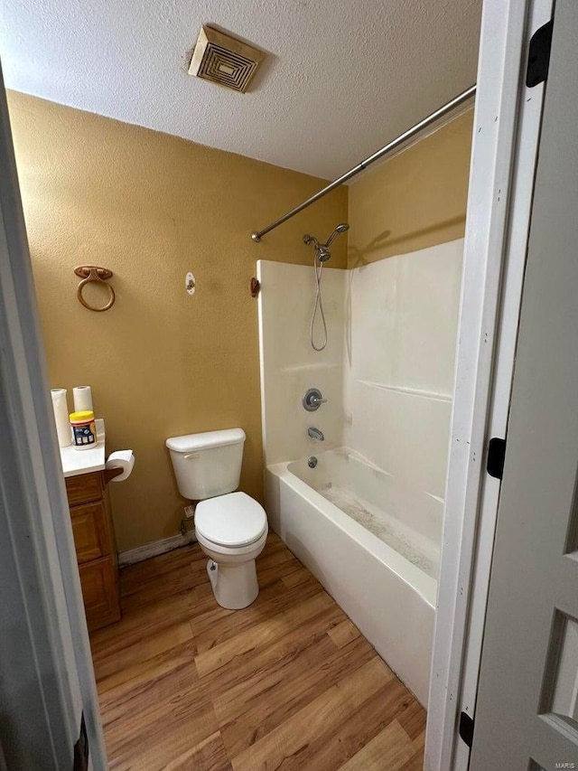 full bathroom with shower / bathtub combination, hardwood / wood-style flooring, vanity, toilet, and a textured ceiling