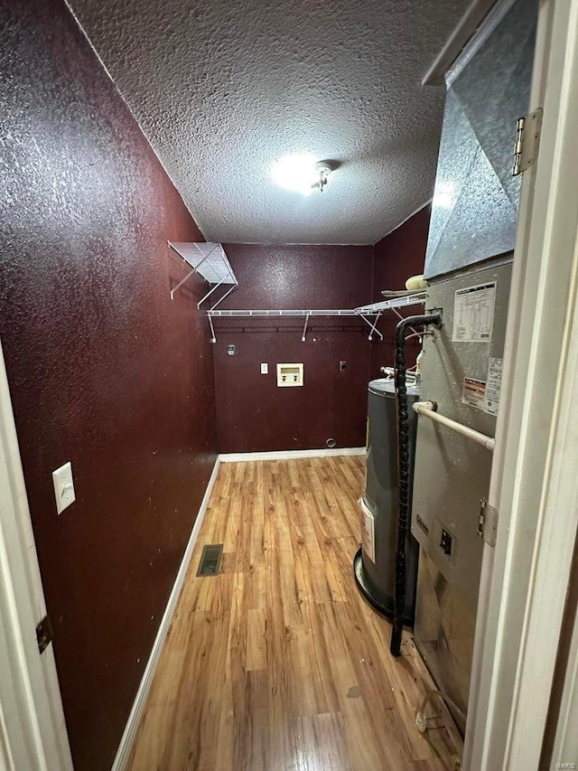 interior space with water heater, a textured ceiling, and light wood-type flooring