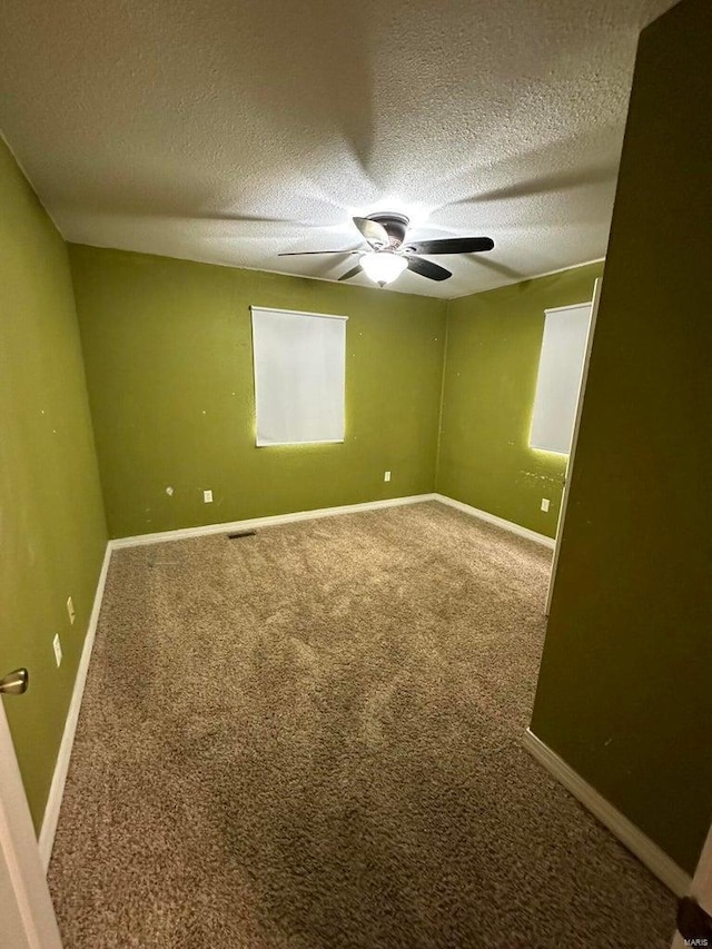 carpeted empty room featuring ceiling fan and a textured ceiling