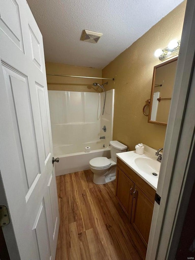 full bathroom featuring bathtub / shower combination, toilet, wood-type flooring, a textured ceiling, and vanity