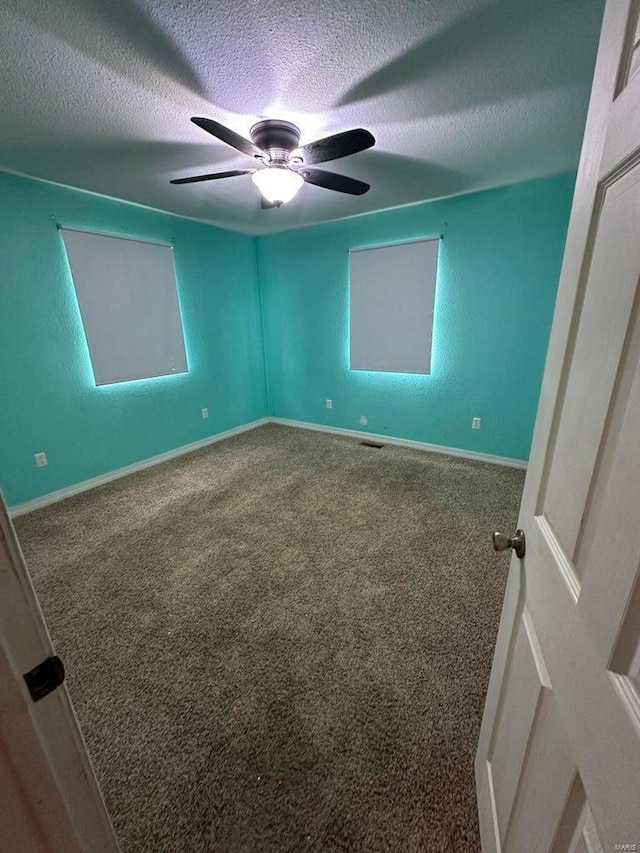 spare room featuring ceiling fan, carpet floors, and a textured ceiling