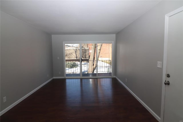 unfurnished room featuring dark wood-type flooring and baseboards