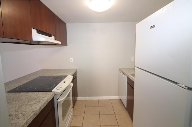 kitchen with light tile patterned floors, light countertops, white appliances, under cabinet range hood, and baseboards