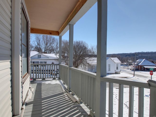 snow covered back of property with covered porch