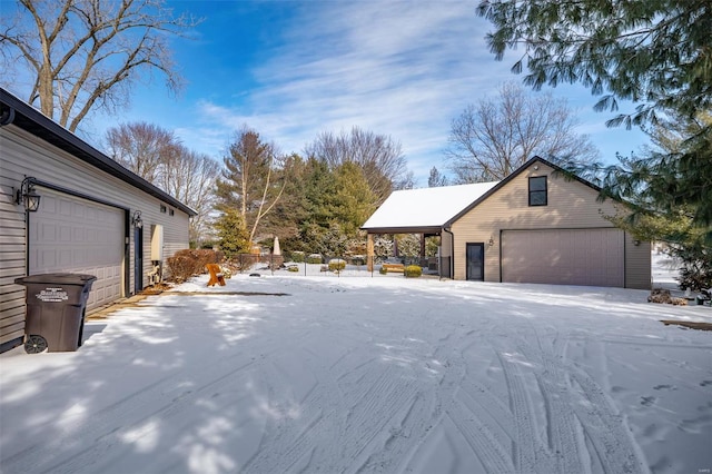 view of snow covered exterior featuring an outbuilding and a detached garage