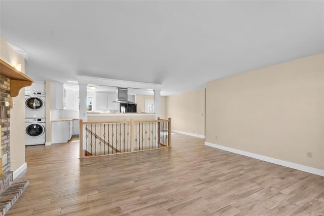 unfurnished living room with stacked washer and dryer and light wood-type flooring