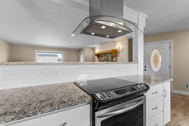 kitchen with light hardwood / wood-style flooring, electric range, tasteful backsplash, island range hood, and white cabinets