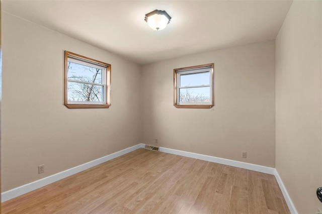 empty room with plenty of natural light and light hardwood / wood-style flooring