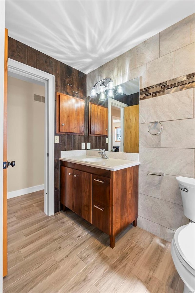 bathroom with vanity, toilet, wood-type flooring, and tile walls