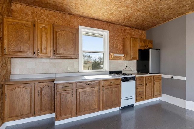 kitchen featuring tasteful backsplash, white gas range, and stainless steel refrigerator