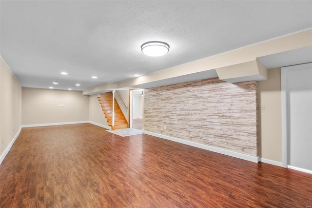 basement featuring wood-type flooring and a textured ceiling