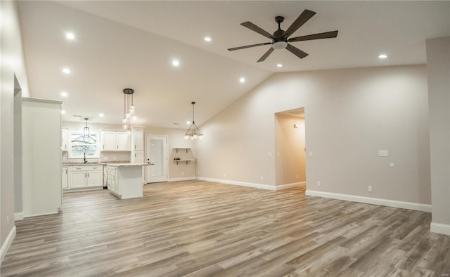 unfurnished living room featuring vaulted ceiling, sink, ceiling fan, and light hardwood / wood-style flooring