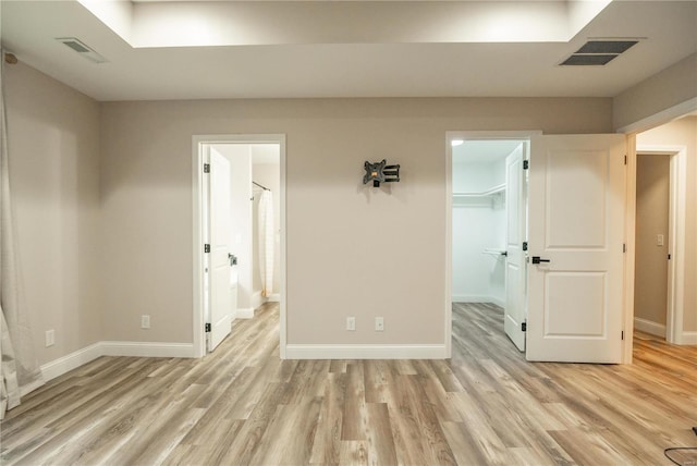 unfurnished bedroom with a spacious closet, a closet, and light wood-type flooring