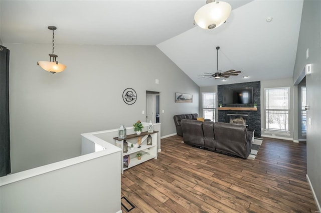 living area with a brick fireplace, plenty of natural light, ceiling fan, and dark wood-type flooring