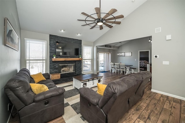 living area featuring a fireplace, a ceiling fan, wood finished floors, high vaulted ceiling, and baseboards