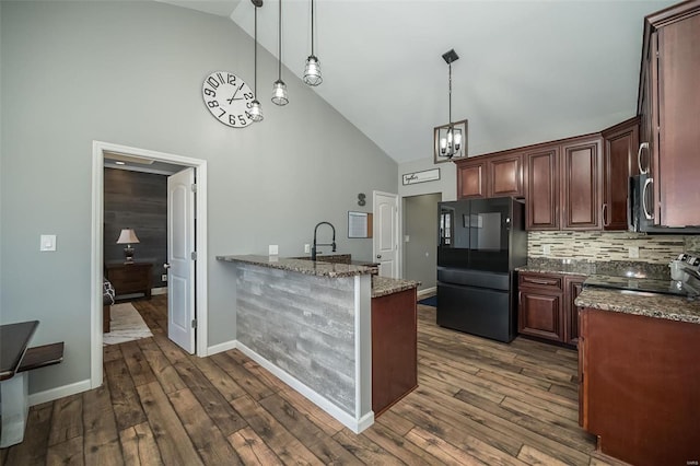 kitchen featuring stainless steel microwave, stove, dark stone countertops, freestanding refrigerator, and pendant lighting