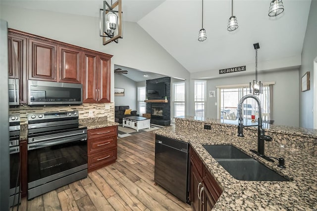 kitchen with hanging light fixtures, appliances with stainless steel finishes, stone countertops, and a sink