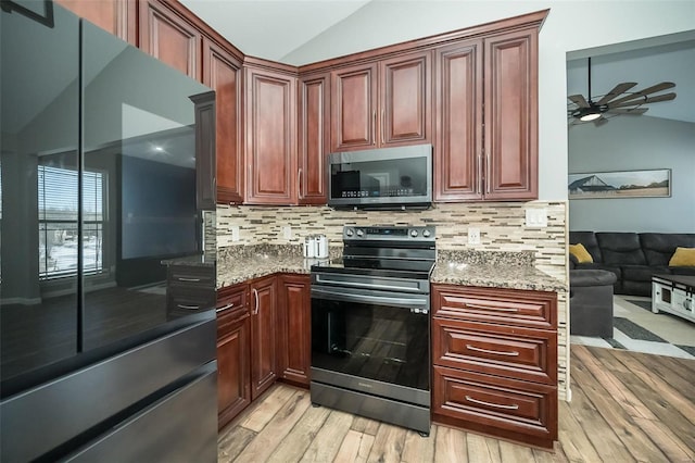 kitchen featuring appliances with stainless steel finishes, lofted ceiling, light wood-type flooring, and light stone countertops