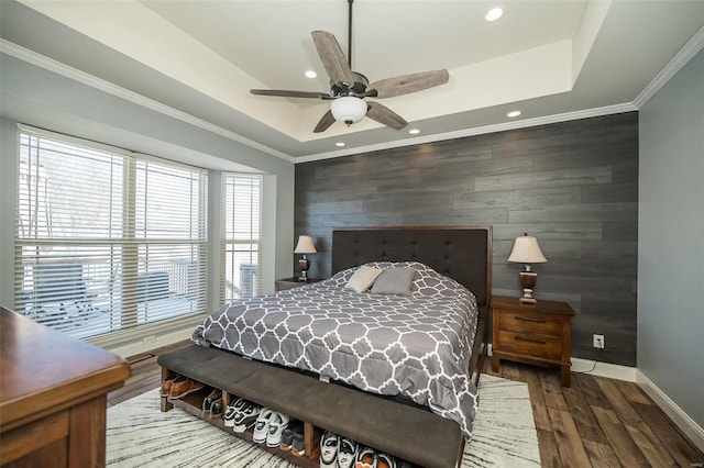 bedroom featuring an accent wall, a tray ceiling, ornamental molding, and baseboards