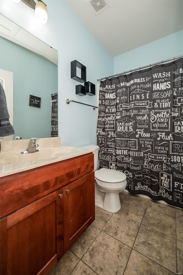 bathroom with toilet, vanity, visible vents, and tile patterned floors