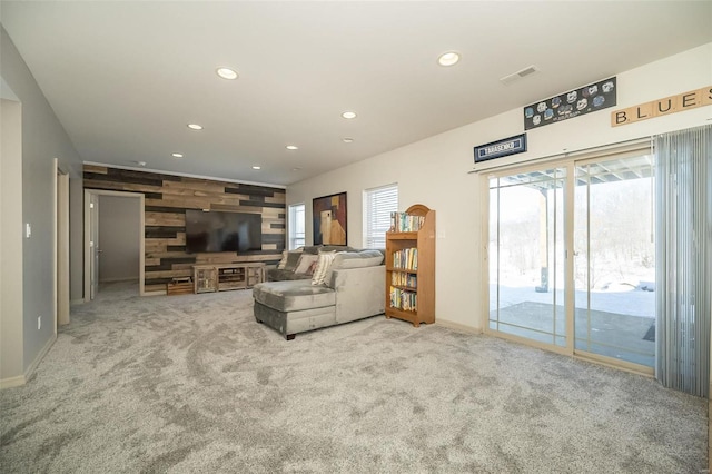 carpeted living area with an accent wall, wood walls, plenty of natural light, and recessed lighting