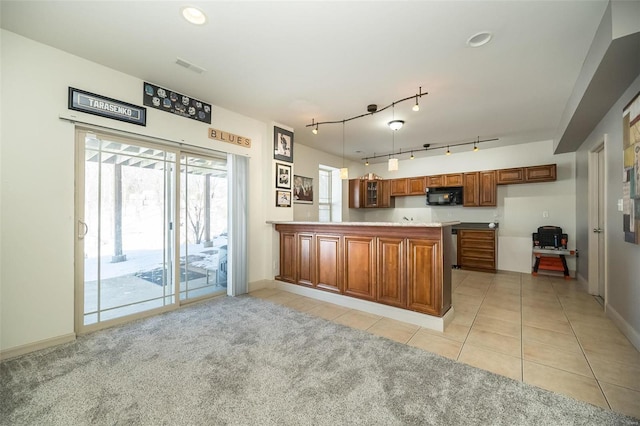 kitchen featuring brown cabinets, black microwave, light countertops, and a peninsula