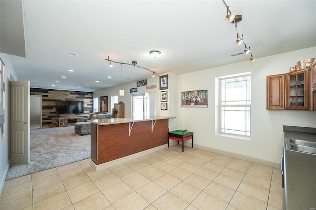 kitchen with brown cabinets, a breakfast bar area, glass insert cabinets, open floor plan, and a peninsula