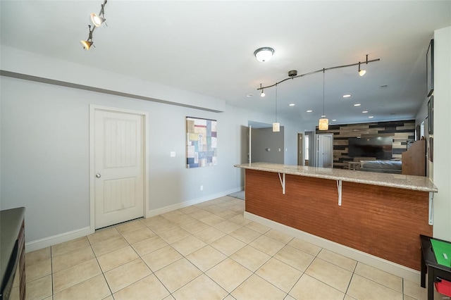 kitchen with open floor plan, light tile patterned flooring, decorative light fixtures, and baseboards