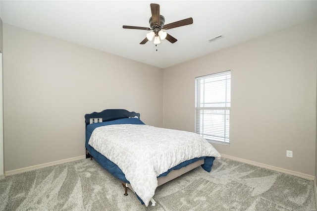 carpeted bedroom featuring a ceiling fan, visible vents, and baseboards