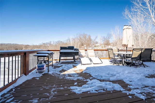 snow covered deck featuring outdoor dining space and a grill